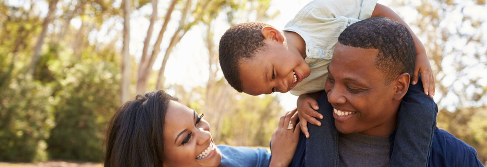 Two adults with a child walking in a park.