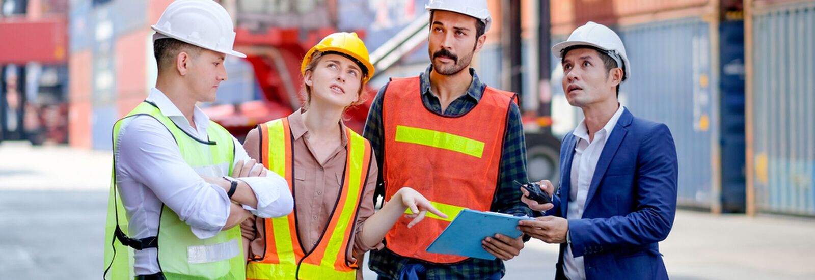 4 construction workers looking over a clip board of papers.